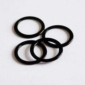 Vier glänzende, schwarze Metall-BH-Ringe sind lose gestapelt. Das Nahaufnahme-Foto betont die hochwertige Verarbeitung und Stabilität dieser 10mm-Ringe.