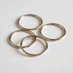 Vier glänzende, silber Metall-BH-Ringe sind lose gestapelt. Das Nahaufnahme-Foto betont die hochwertige Verarbeitung und Stabilität dieser 16mm-Ringe.