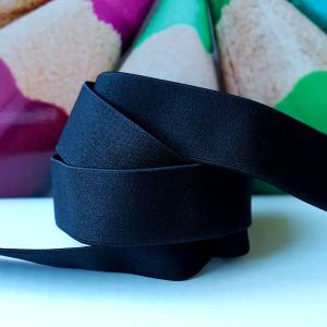 Schwarzes Falzgummiband 3cm aufgerollt. Die Detailansicht zeigt die leicht strukturierte Oberfläche des elastischen Einfassgummis für Sportbekleidung.