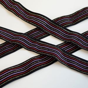 Leicht strukturiertes, mittelstarkes Gummiband in schwarz mit Glitzerstreifen und weitere Streifen in flieder und rot - für Bekleidung und Unterwäsche.