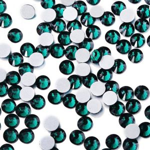 Nahaufnahme glänzender Emerald Hotfix Glas-Strasssteine (SS30). Zeigt Details der Facetten und den schmelzenden Kleber für Textilien. Ideal für DIY.