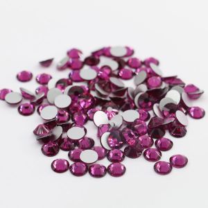 Nahaufnahme glänzender Lotus Purple Hotfix Glas-Strasssteine (SS10). Zeigt Details der Facetten und den schmelzenden Kleber für Textilien. Ideal für DIY.