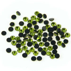 Nahaufnahme glänzender Olivine Hotfix Glas-Strasssteine (SS10). Zeigt Details der Facetten und den schmelzenden Kleber für Textilien. Ideal für DIY.