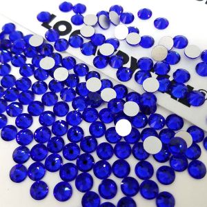 Nahaufnahme glänzender Sapphire Hotfix Glas-Strasssteine (SS6). Zeigt Details der Facetten und den schmelzenden Kleber für Textilien. Ideal für DIY.