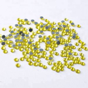 Nahaufnahme glänzender Citrine Hotfix Glas-Strasssteine (SS10). Zeigt Details der Facetten und den schmelzenden Kleber für Textilien. Ideal für DIY.