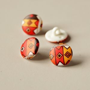 Kunststoffknopf in orange-rot mit retro Muster. Ösenknopf mit 13mm Durchmesser.