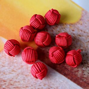 Zehn kugelförmige Knäuelknöpfe in der Farbe Rot. Die Oberfläche aus feiner Satinkordel imitiert die Wicklung eines Wollknäuels und verleiht eine tolle Haptik.