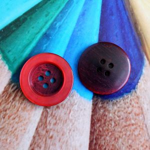 Roter 20mm Kunststoffknopf mit Kunstharz-Schimmer. Ansicht der glänzenden Vorderseite und der Rückseite mit 4 Löchern. Stabiler Knopf bei Spitzentraum.ch.