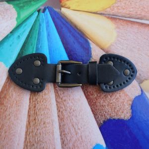 Riemenverschluss für Taschen aus schwarzem Kunstleder, 14cm lang, kupferfarbene Schnalle und Zierösen, dreieckige Endstücke zum Aufnähen.